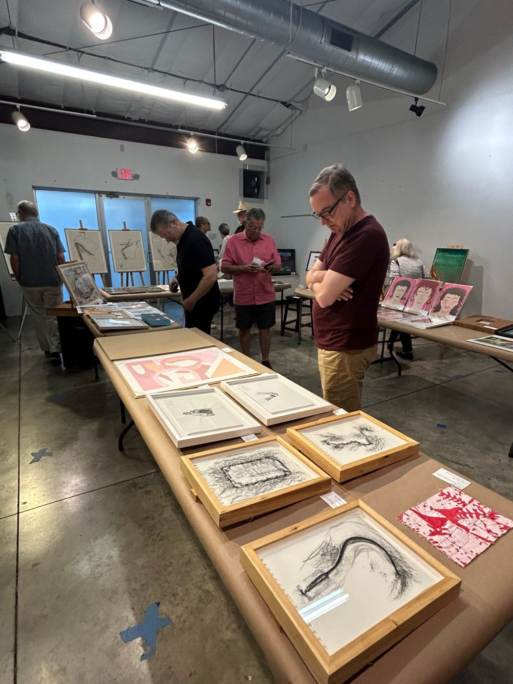 A visitor looking at framed drawings on a long table at the Houston fair