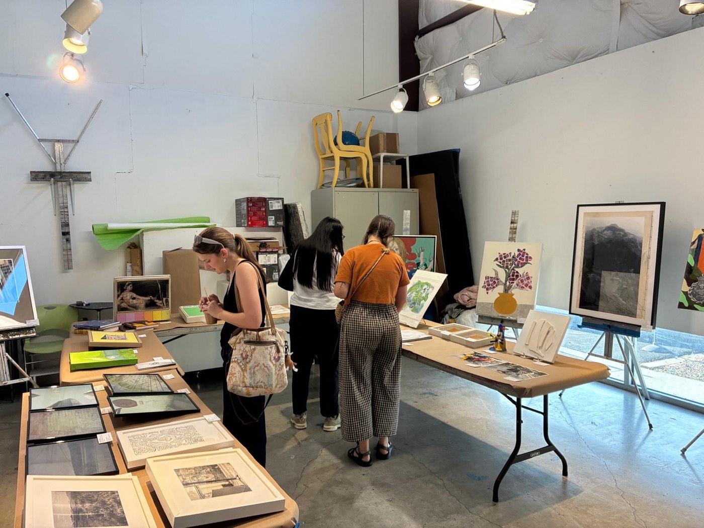 Visitors looking at prints and paintings on easels and tables at the Houston fair