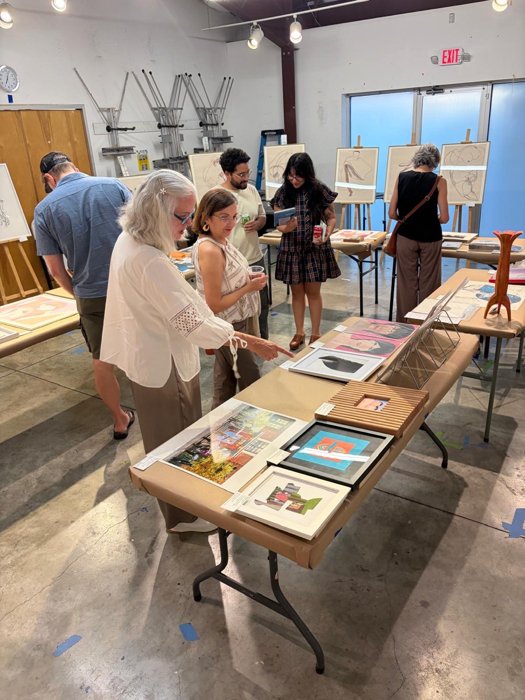 Visitors pointing at and discussing artworks at the Houston fair